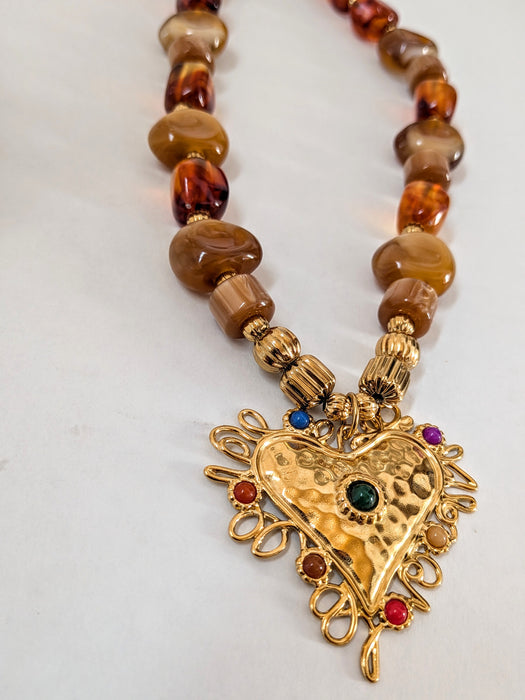 Necklace with a gold heart pendant and brown beads on a white background