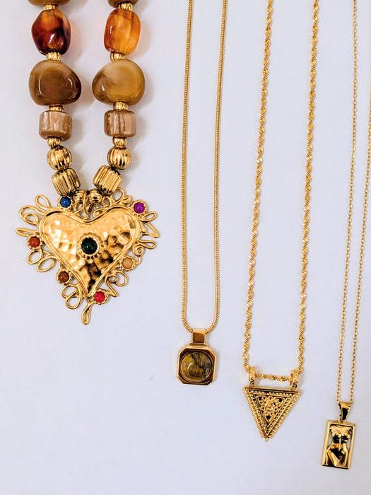 Three gold necklaces with various pendants on a white background