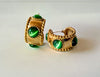 Gold earrings with green gemstones on a light gray background
