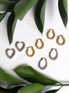 Set of gold and silver hoop earrings on a white background with green leaves.