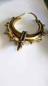 Gold hoop earring with decorative elements on a white background