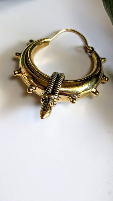 Gold hoop earring with decorative elements on a white background
