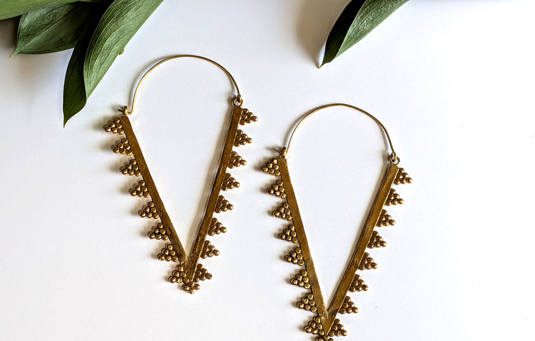 Pair of gold hoop earrings with leaf-like designs on a white background