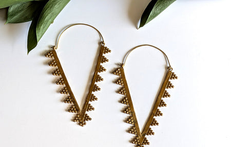 Pair of gold hoop earrings with leaf-like designs on a white background