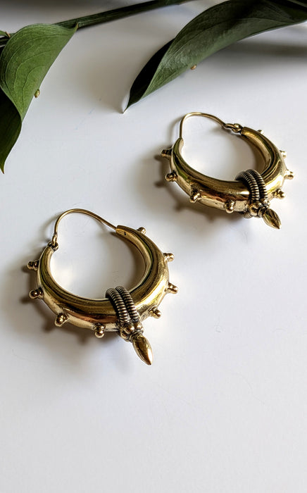 Gold hoop earrings with spike details on a white background