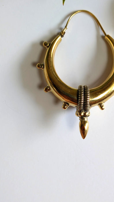 Gold hoop earring with a textured design on a white background